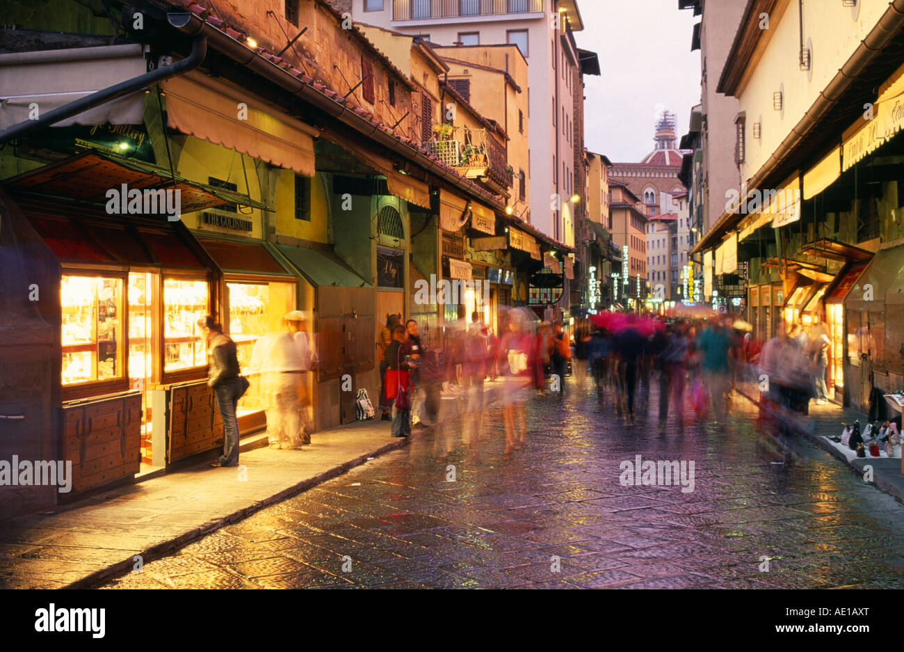 Italien Toskana Florenz Ponte Vecchio Straßenszene in der Abenddämmerung mit Ladenfronten entlang der Brücke und Menschen in Bewegungsunschärfe Stockfoto