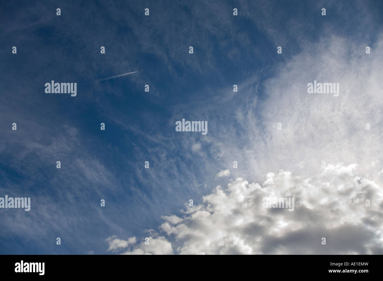Flugzeuge verlassen eine Dampfspur in blauen Himmel mit wispy Weiße Wolken Stockfoto