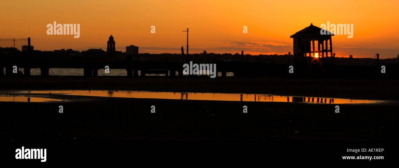 Panorama-horizontale Foto einer verfallenen Sihouetted Hütte gegen das Leuchten von einem Sonnenuntergang. Schaute nach Birkenhead Stockfoto