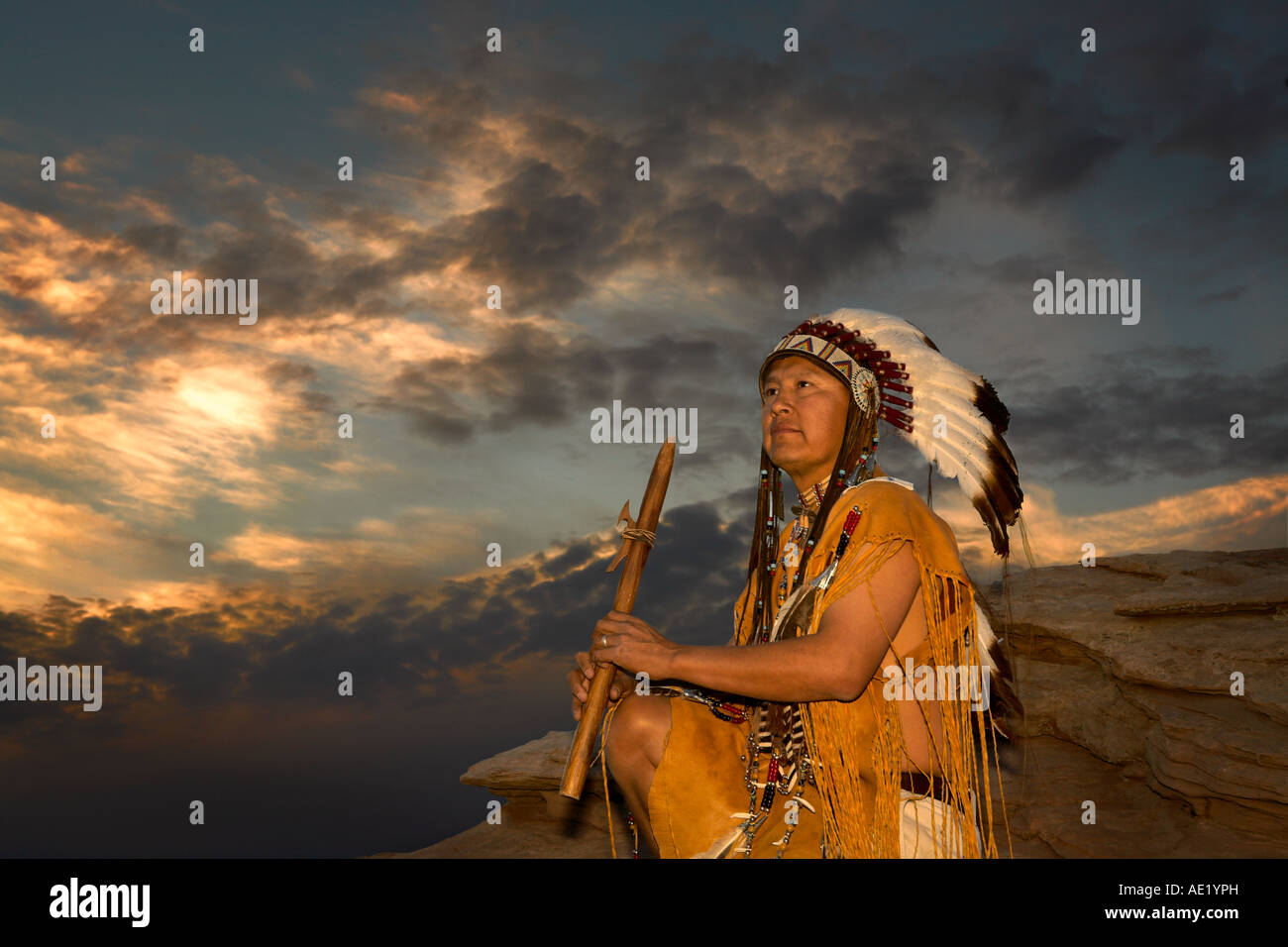 Native American Indian Mann mit kulturellen Outfit einheitliche Kopfschmuck Federn Design Muster Leder Band Natur Sonnenuntergang Sonnenaufgang Stockfoto