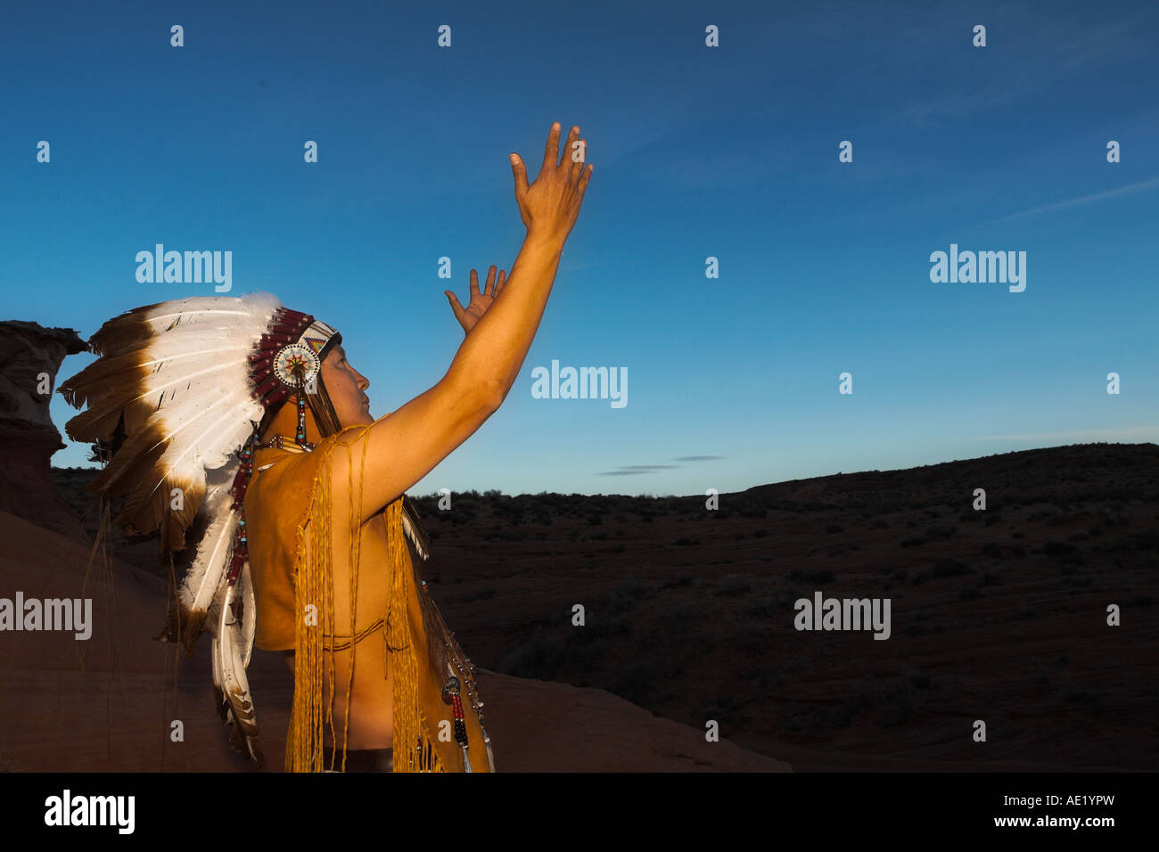 Native American Indian Mann mit kulturellen Outfit einheitliche Kopfschmuck Federn Design Muster Leder Band Natur Sonnenuntergang Sonnenaufgang Stockfoto