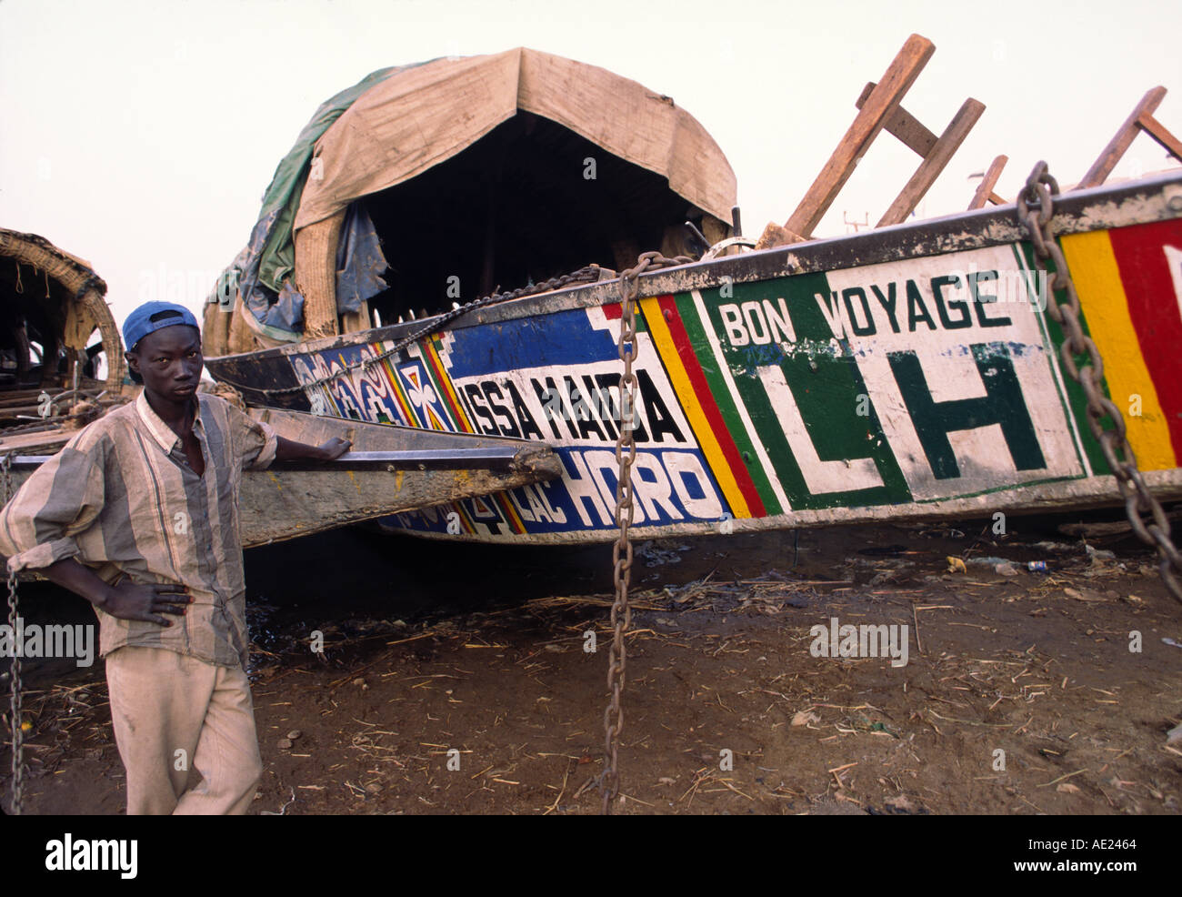 Ein Fährmann steht neben seinem Pirougue, einem traditionellen Holzboot zum Verschieben von Personen und Gütern auf dem Niger in Mali Stockfoto