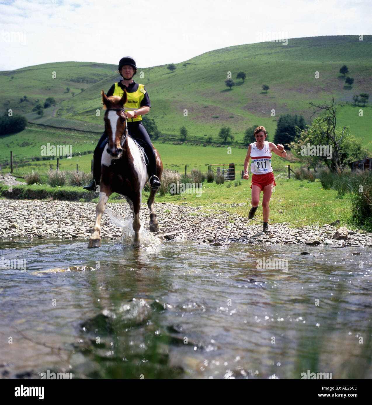 Eine Frau läuft und ein Pferd im Galopp über den Abergwesyn Ford im Mensch gegen Pferd Rennen in Llanwrtyd Wells Wales UK KATHY DEWITT Stockfoto