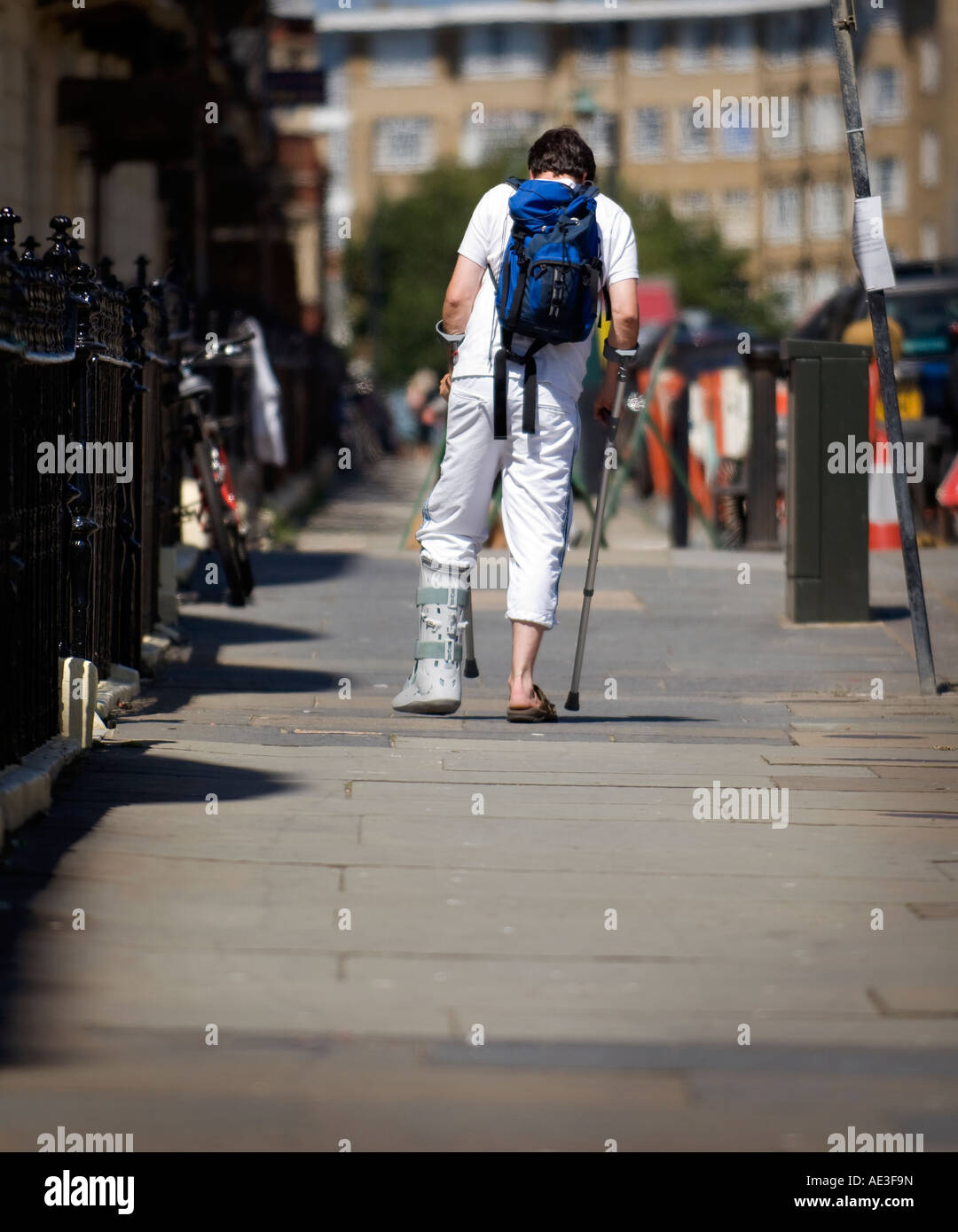 Ein junger Mann mit Bein in Gips auf der Straße. Bild von Jim Holden. Stockfoto