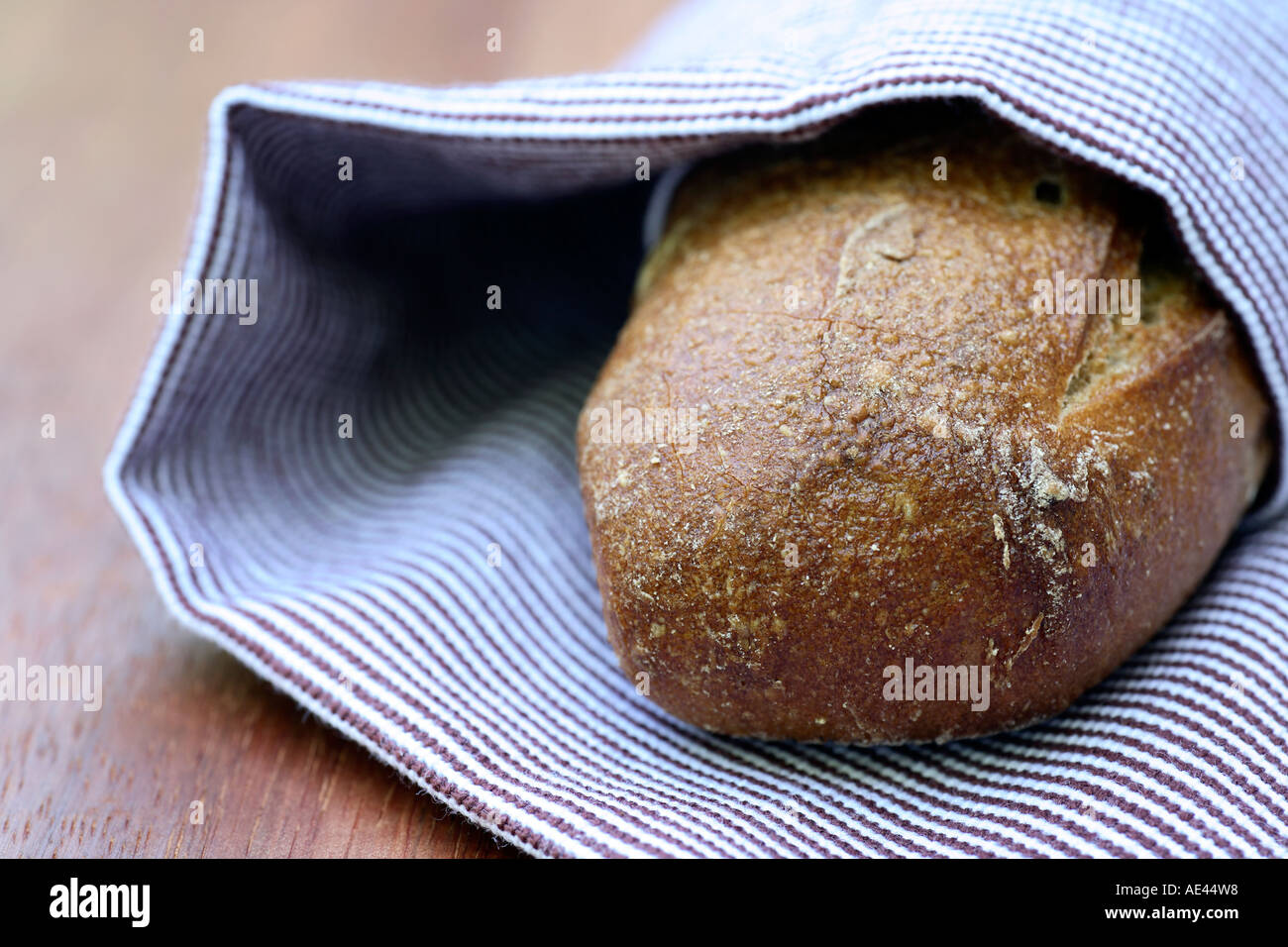 Frisch gebackenes knuspriges Brot eingewickelt in Tuch auf dem Holztisch. Stockfoto