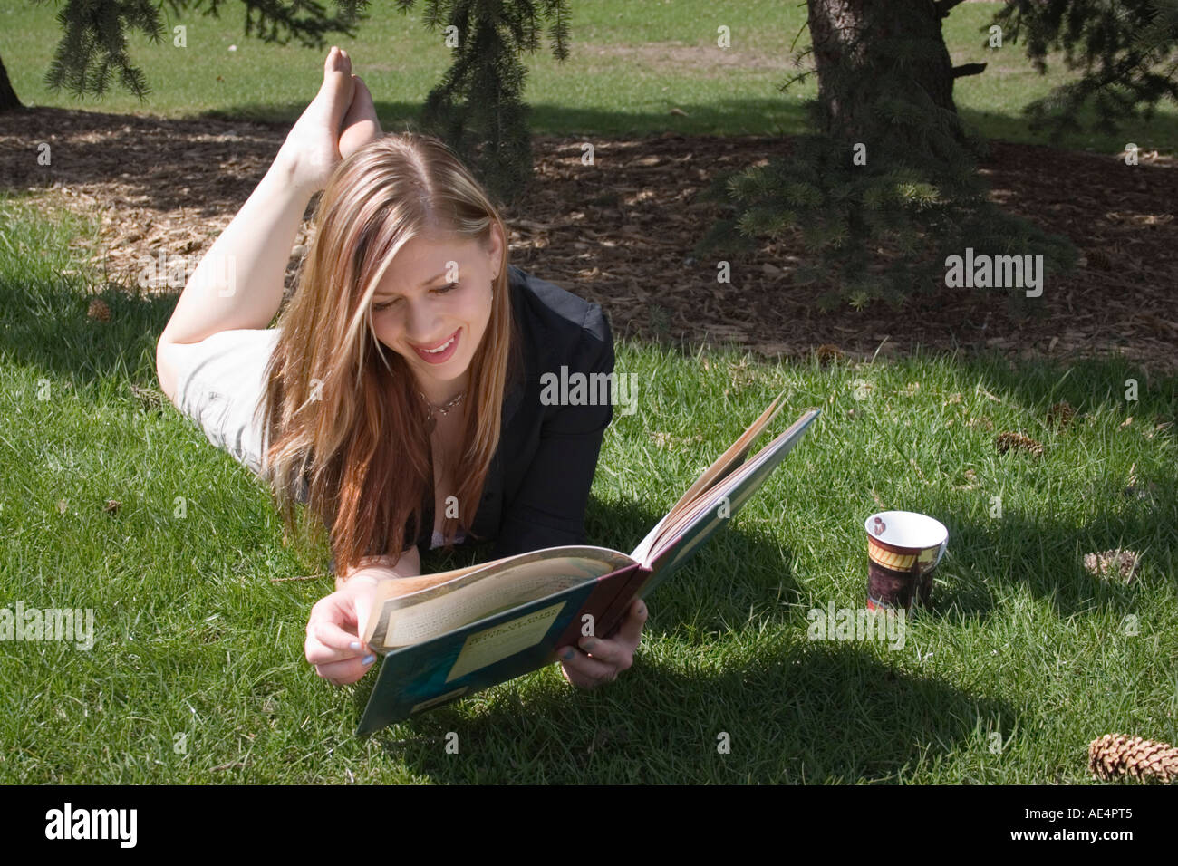 Mädchen-Lesebuch im Park in Calgary Alberta Kanada Stockfoto