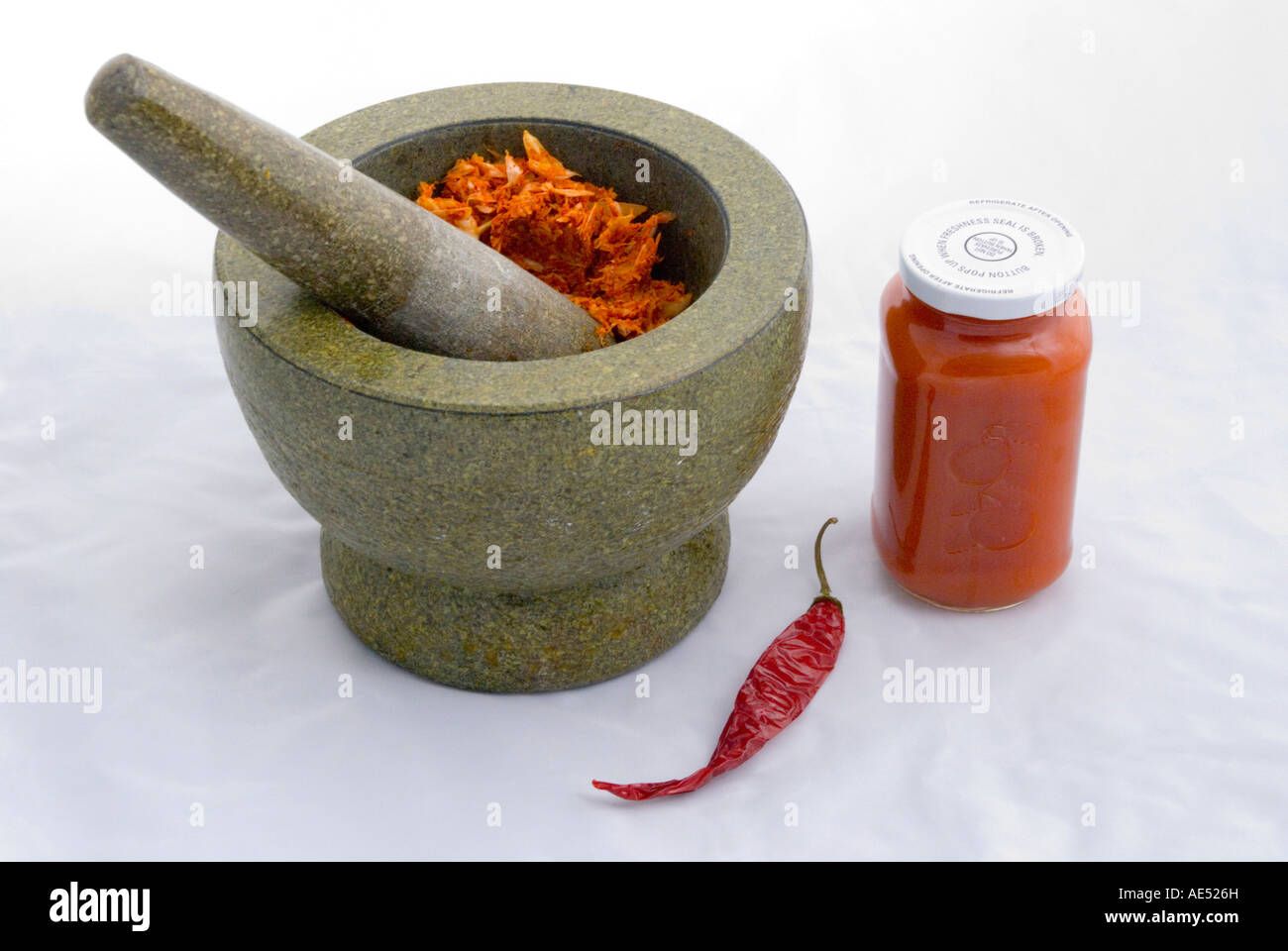 Eine hausgemachte scharfe Knoblauch-Chili-Paste, die in einem traditionellen schweren chinesischen Stößel und Mörser gehackt wird Stockfoto