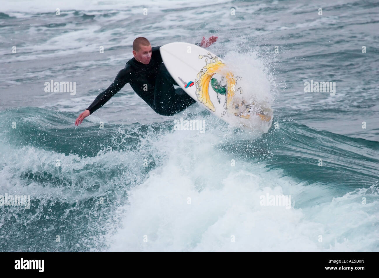 Surfer in einen Taucheranzug Luft auf seinem Surfbrett, da er eine Welle surfen auf dem Pazifischen Ozean Santa Cruz Kalifornien springt Stockfoto