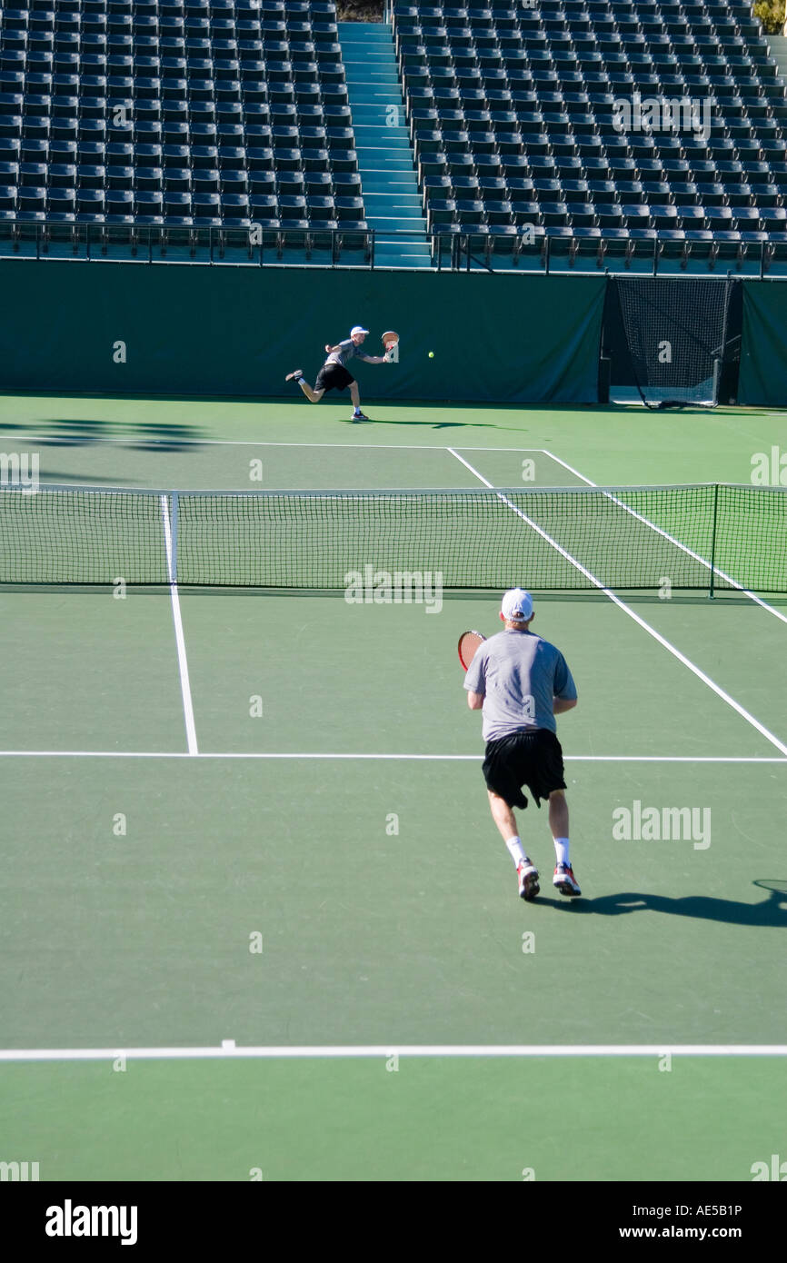 Zwei Männer spielen Tennis auf dem Stadion Tennisplatz mit einem Mann Running Back und erreichen um den Ball mit einem Vorhand Schuss zurück Stockfoto