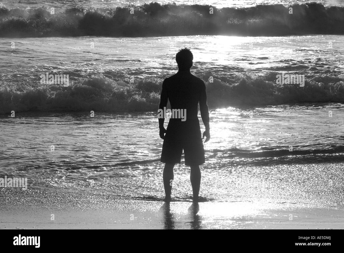 Silhouette der Mann, der im nassen Sand am Strand mit Blick auf pazifischen Ozeanwasser Stockfoto