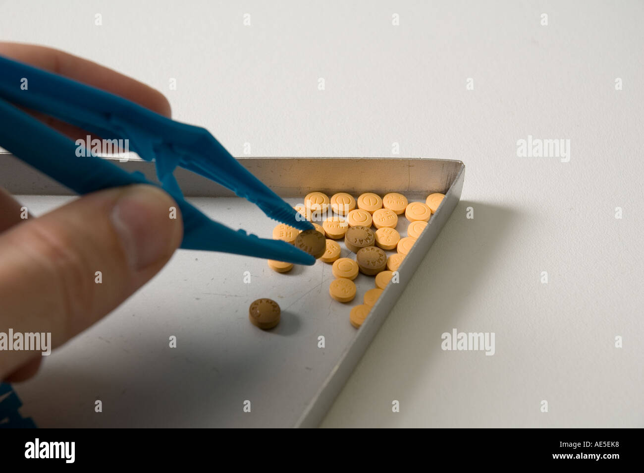 Ein Mann verwendet Tweesers, um verschiedene Tabletten aus einer Zählung Dreieck herausgreifen Stockfoto
