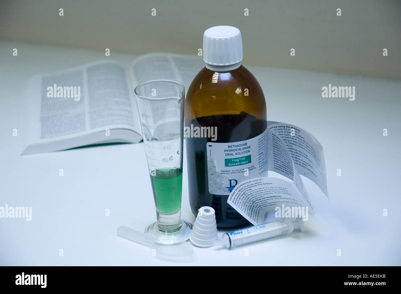 Methadon-Lösung in eine Flasche und Mess Krug mit Applikationsspritze und Nachschlagewerk Stockfoto