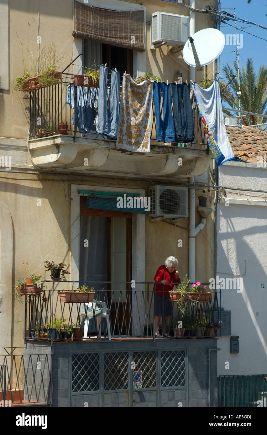 Alte Frau, die Pflege der Pflanzen auf Balkon in Acitrezza, Sizilien Stockfoto
