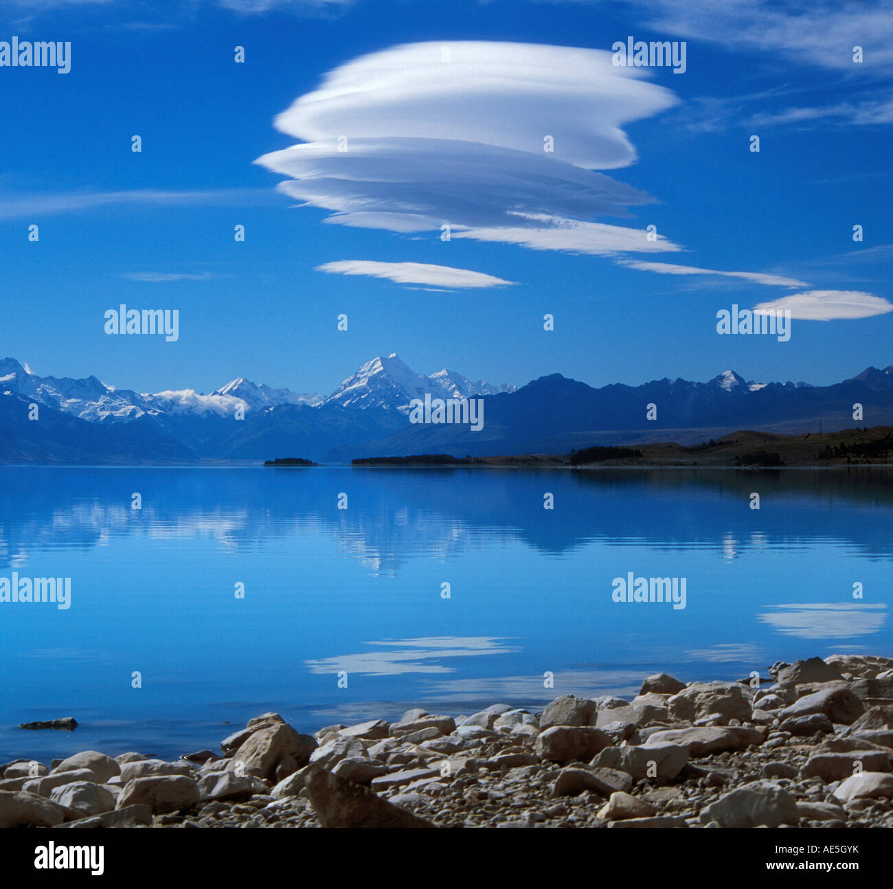 Seidige Wolke in einem tiefblauen Himmel schwebt über Mt. Cook vom türkisblauen See mit felsigen Ufer Südinsel Neuseeland Stockfoto