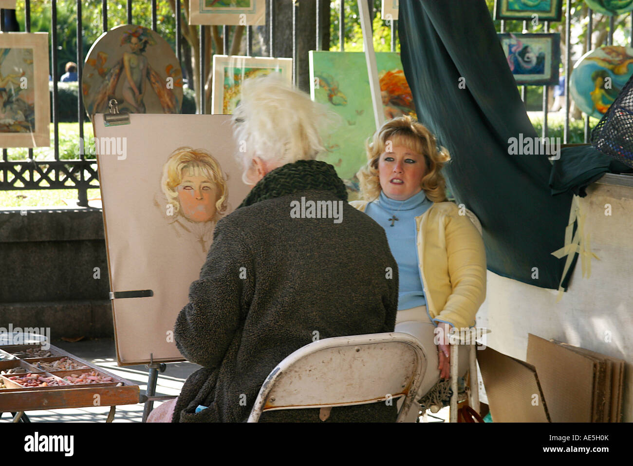 Blonde Frau sitzt für Portrait als Straßenkünstler zieht ihr Gesicht mit Kreide Buntstifte French Quarter New Orleans Louisiana Stockfoto
