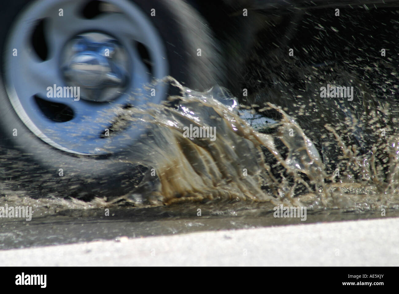 Wasser aus einer schlammigen Pfütze planschen als ein Lkw Rad-Antriebe durch sie Stockfoto
