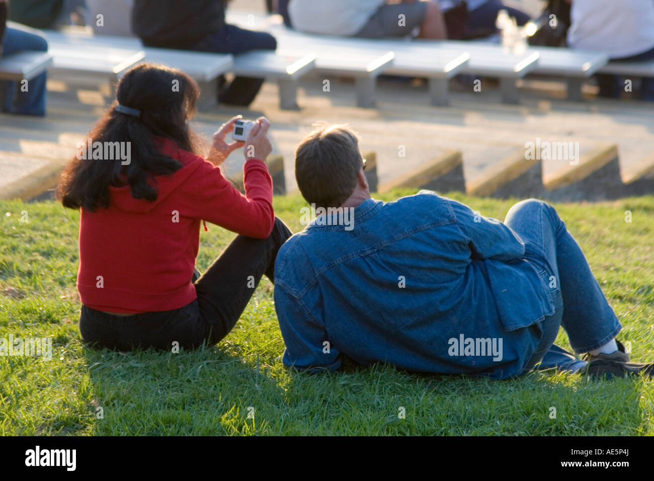 Frau sitzt auf dem Rasen mit ihrem Ehemann nehmen Foto mit Digitalkamera Stockfoto
