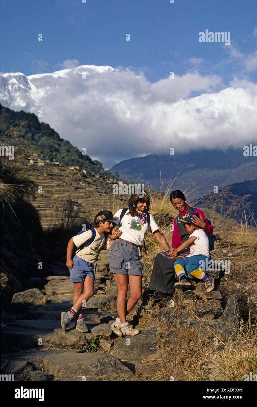 Christine Kolisch und Bodhi Garrett begrüßen eine Sherpani & ihres Sohnes in der Nähe von Siklis mit Lamjung Himal hinter NEPAL HIMALAYA Stockfoto