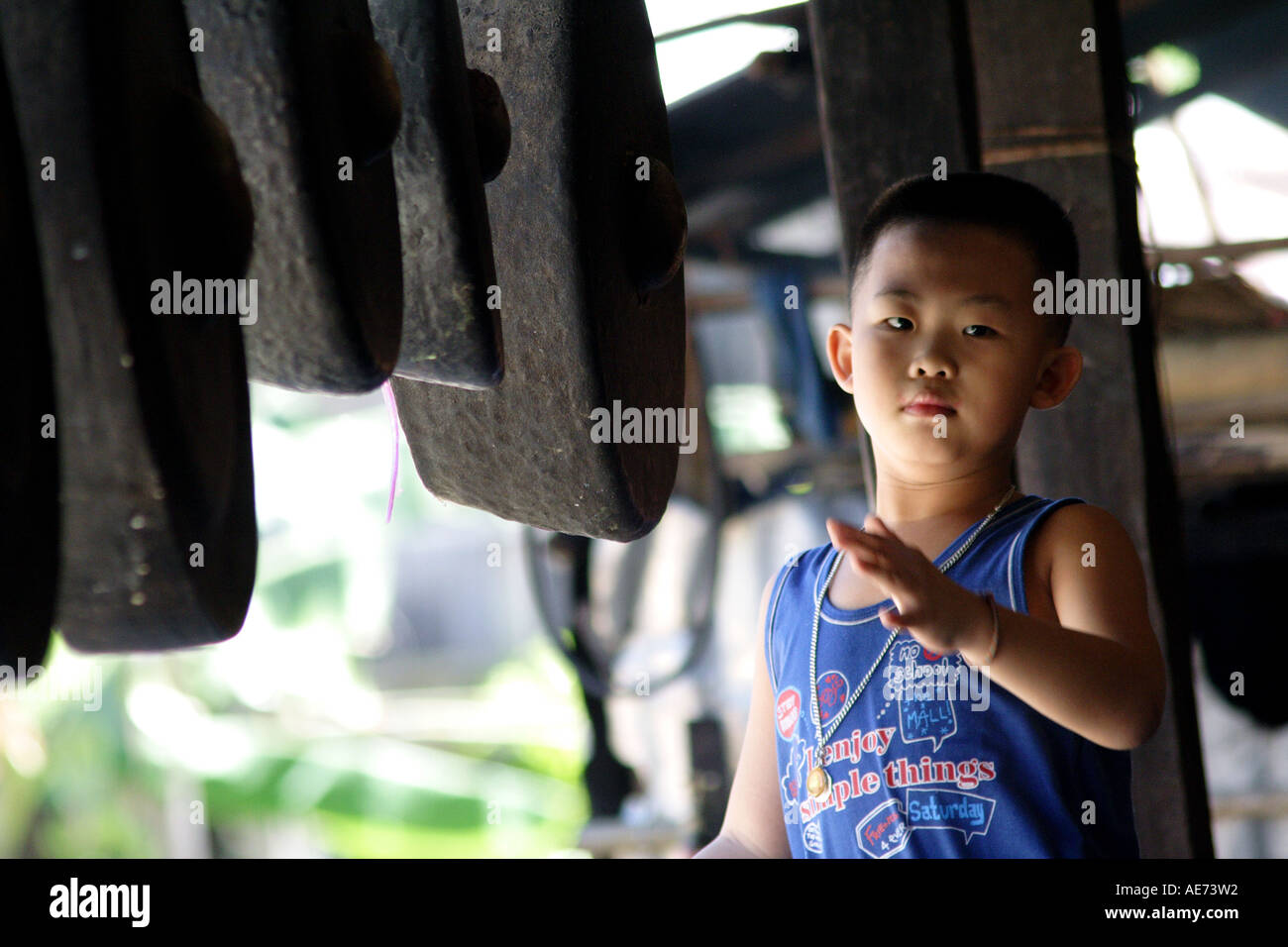 Malaysische Boy trifft ein traditioneller Gong oder Messing Drum, Kamung Annah Rais, eine Bidayuh Longhouse, Sarawak, Borneo, Malaysia Stockfoto