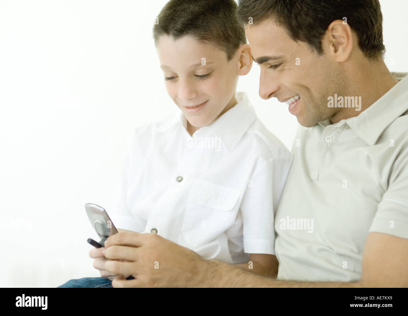 Mann und Sohn Blick auf Handy zusammen Stockfoto