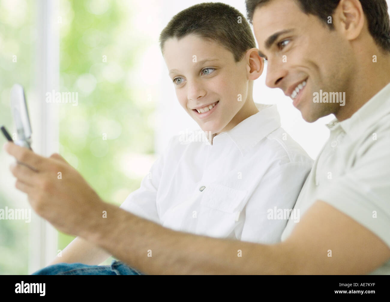 Mann und Sohn Blick auf Handy Stockfoto