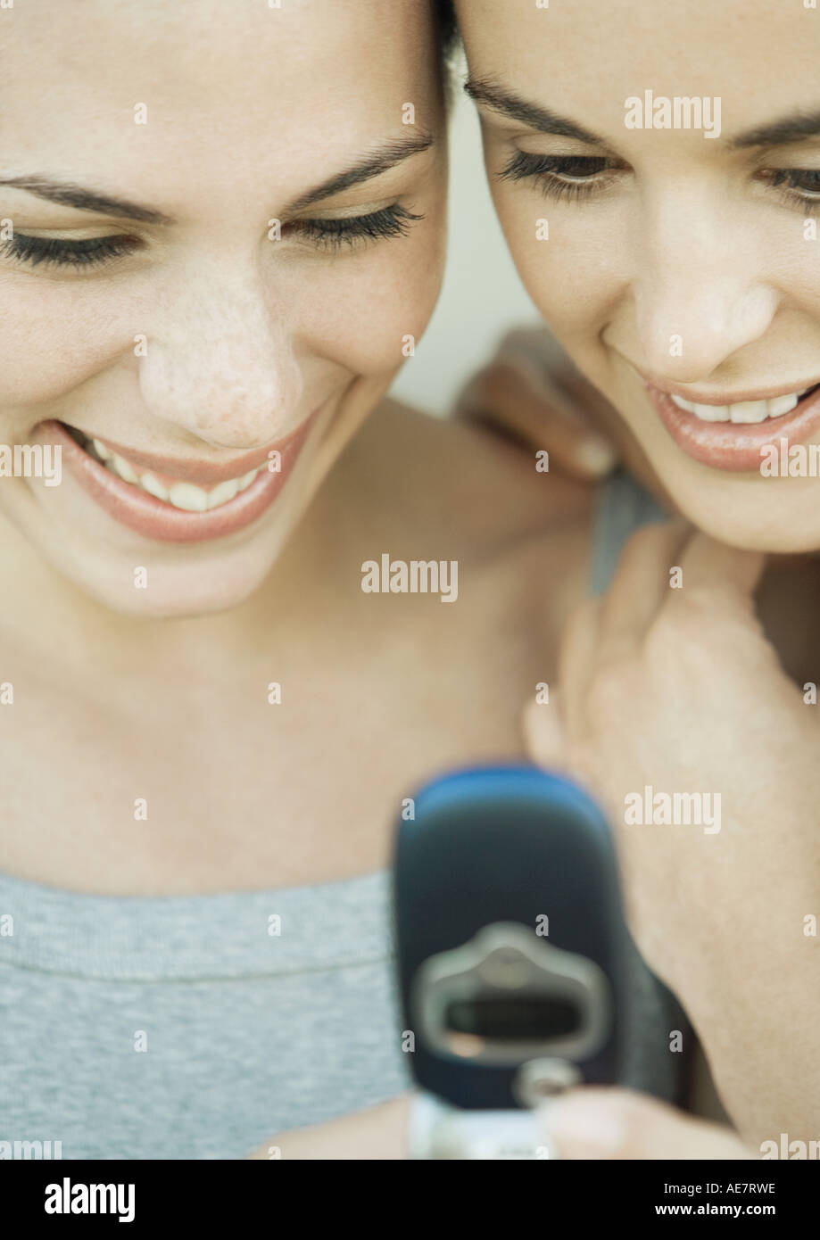 Zwei junge Frauen nebeneinander blickte auf ein Handy, beide Lächeln, extreme Nahaufnahme Stockfoto