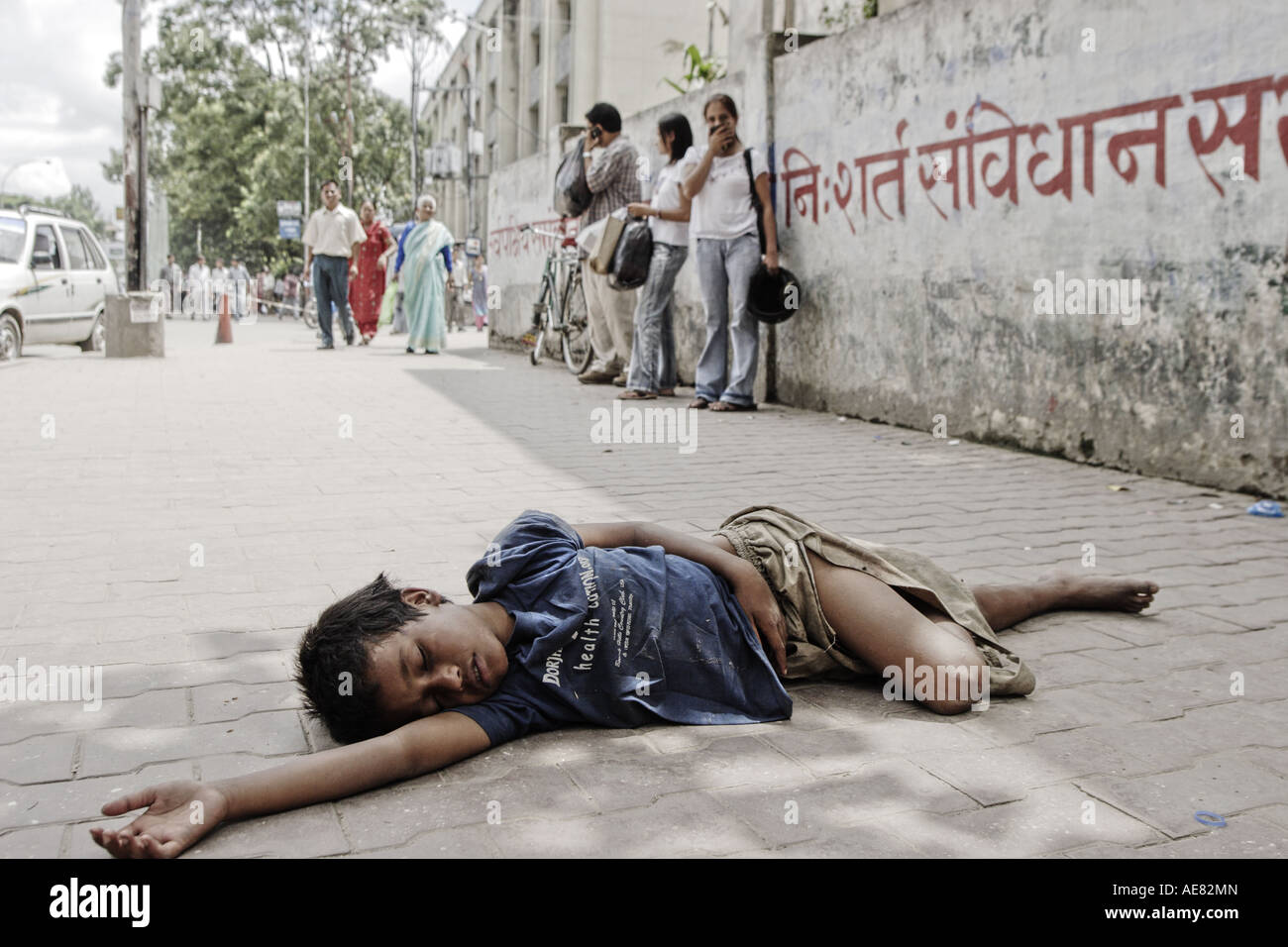 11 Jahre alter Junge, der auf der Straße gelebt hat, seit er 9, Shopper im Hintergrund, Kathmandu Nepal 2006 war Stockfoto