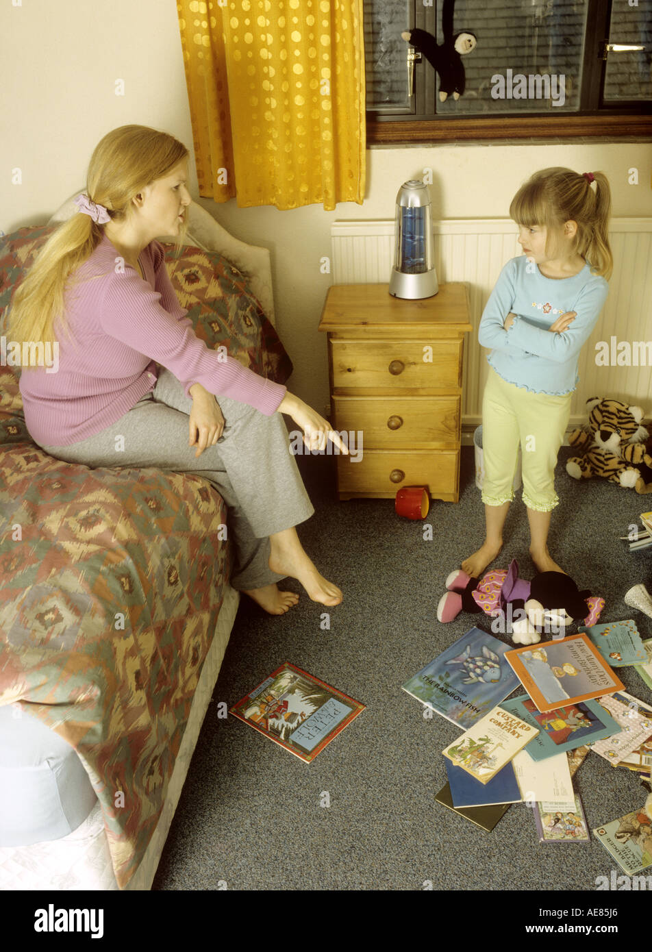 Mutter erzählte Sie ihr Kind in ihrem chaotisch Schlafzimmer Stockfoto