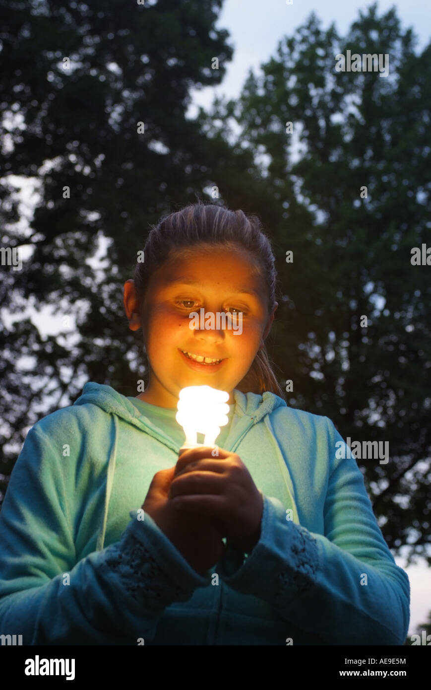 Mädchen im Freien eine fluoreszierende Energie Saver Glühlampe in ihren Händen hält Stockfoto