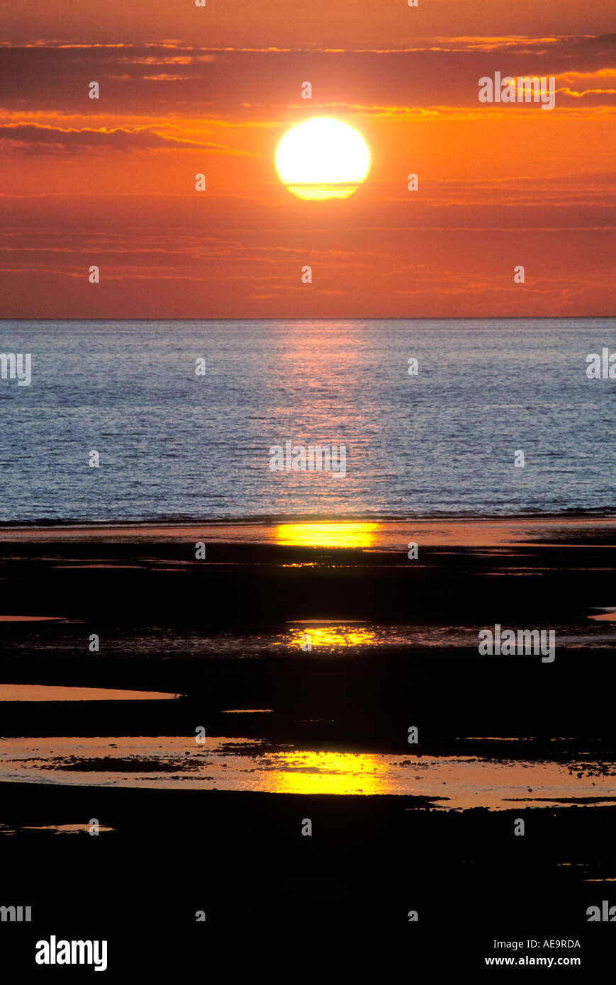 dramatischen Sonnenuntergang über Meer und Strand mit Reflexionen Stockfoto