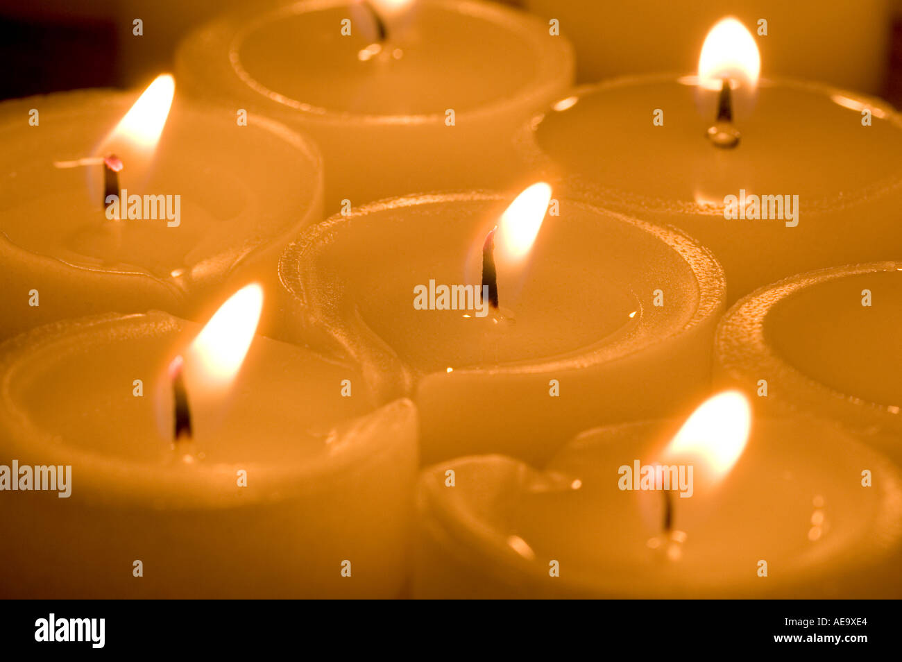Teelichter zusammengefasst beleuchtet vor dunklem Hintergrund eine farbige orange reflektierende Beleuchtung natürliche Kerzenlicht o Stockfoto