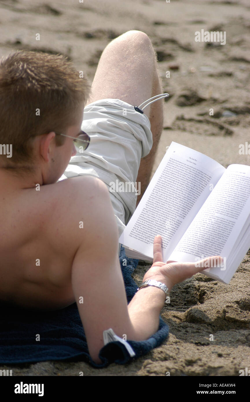männliche Studenten ein Text-Buch am Strand von Aberystwyth Wales UK Stockfoto