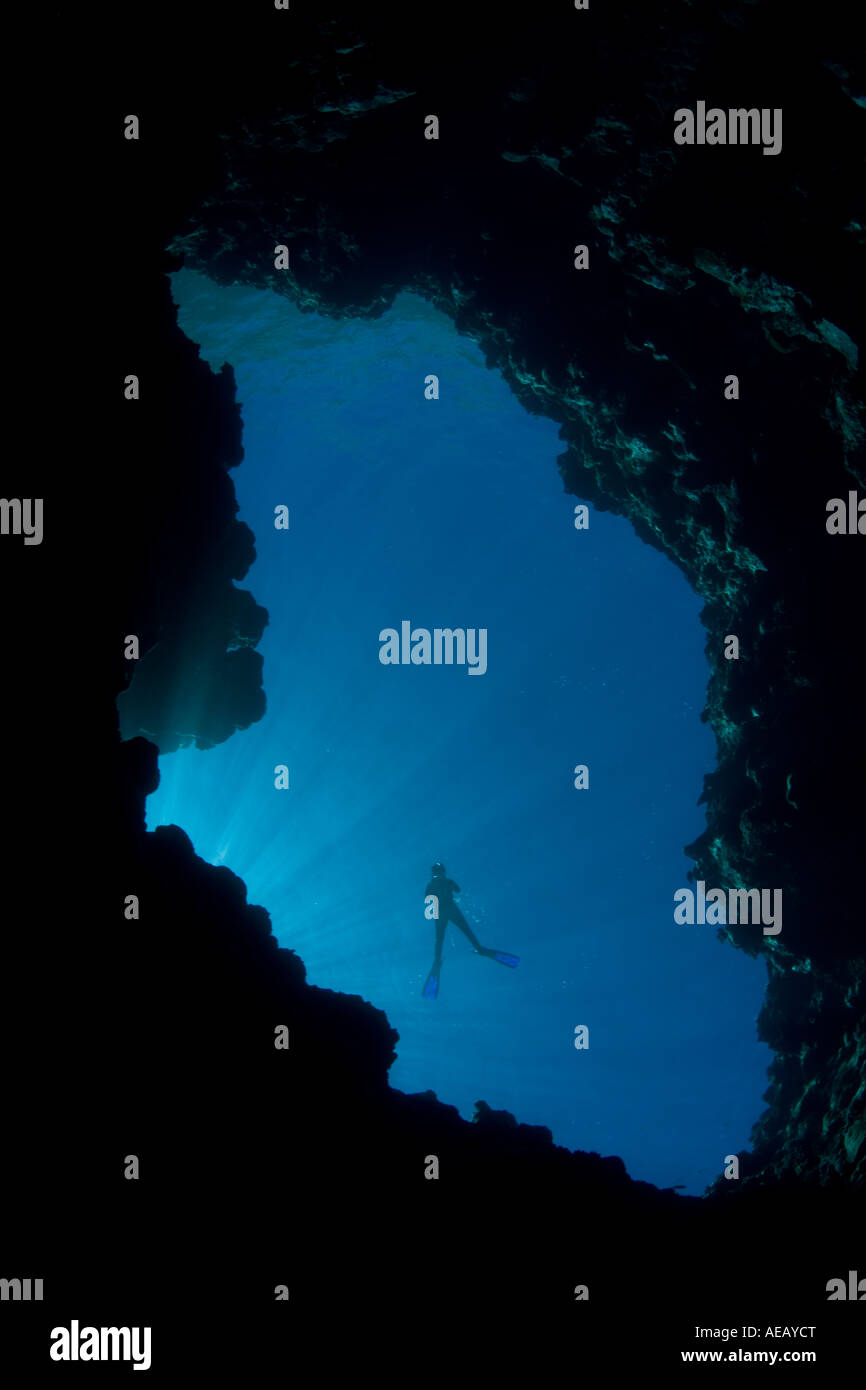 Ein schnorchler sieht hinunter in die dunklen Tiefen unterhalb in einem natürlichen Blue Hole, geformt wie das Dach einer Höhle eingestürzt vor Äonen in der Republik Palau. Stockfoto