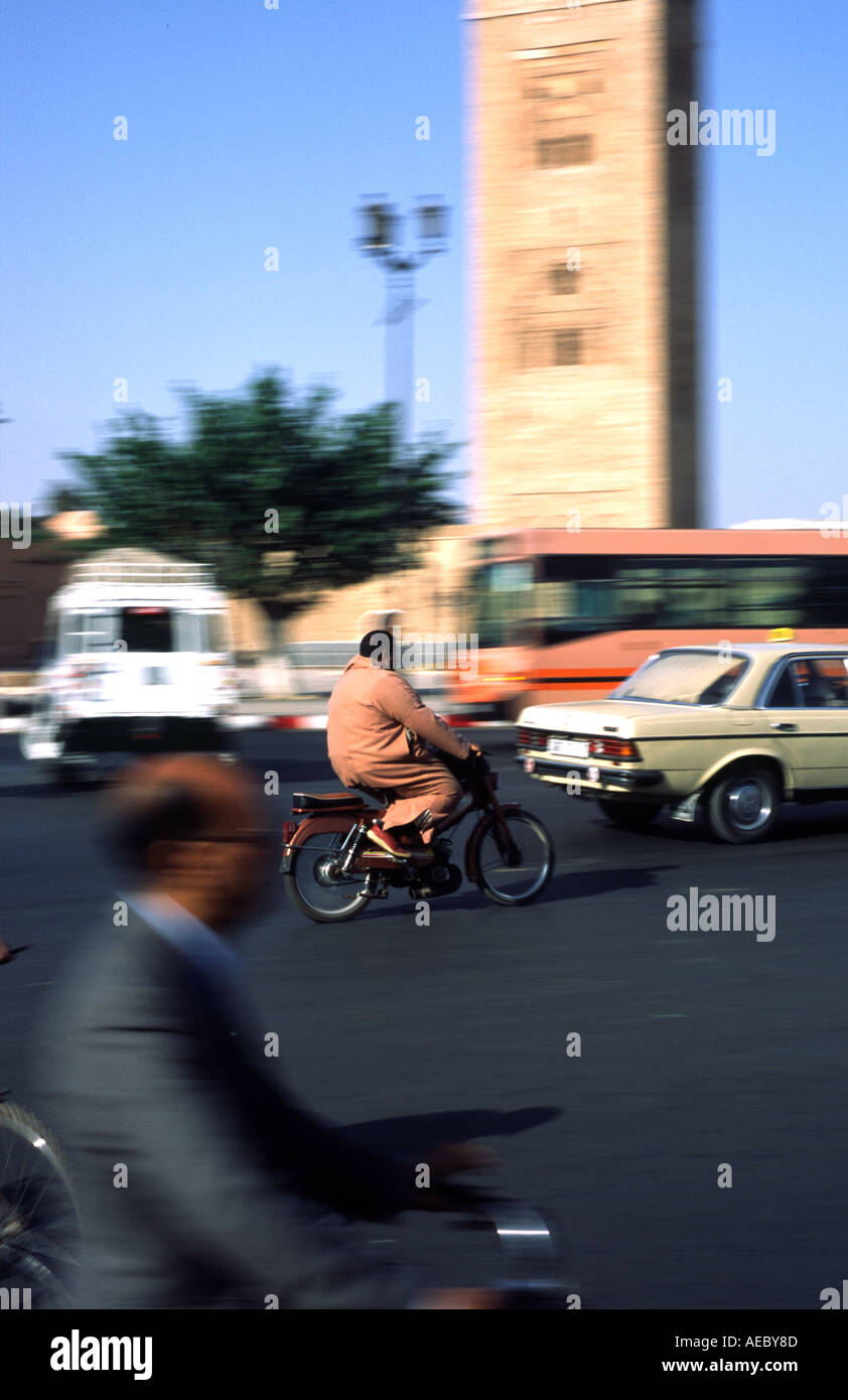 Ein Radfahrer Moped Fahrer Taxi und Bus fahren gleichzeitig die Koutoubia-Moschee in Marrakesch, Marokko Stockfoto