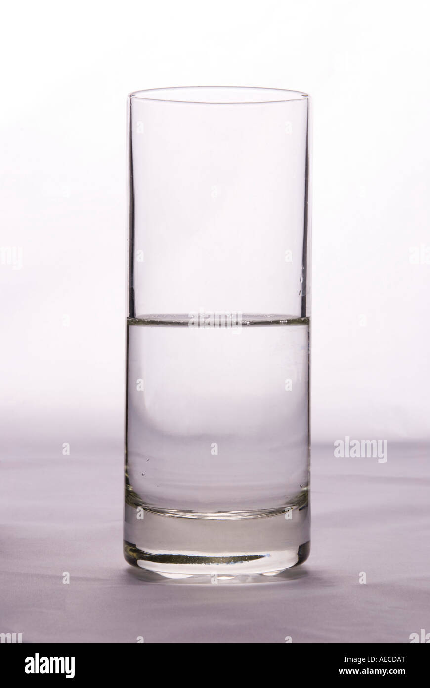 Ein Glas, das halb voll oder halb leer ist, um die Idee von Pessimismus oder Optimismus auf einem einfachen Hintergrund zu veranschaulichen Stockfoto