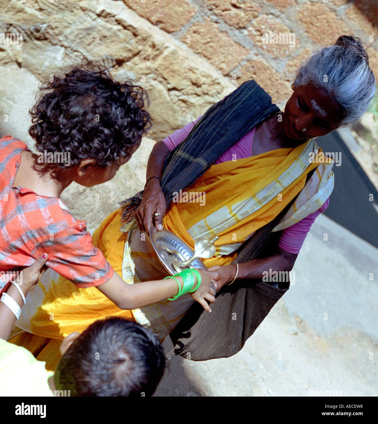 Eine alte Dame gekleidet in Saree akzeptiert Arme von zwei Kindern, Kerala, Indien Stockfoto