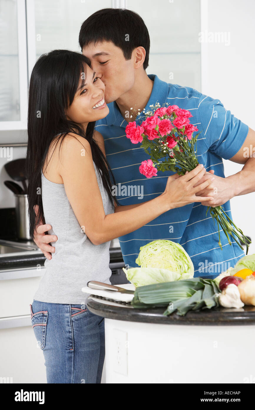Asiatischer Mann Freundin küssen und geben ihre Blüten in Küche Stockfoto