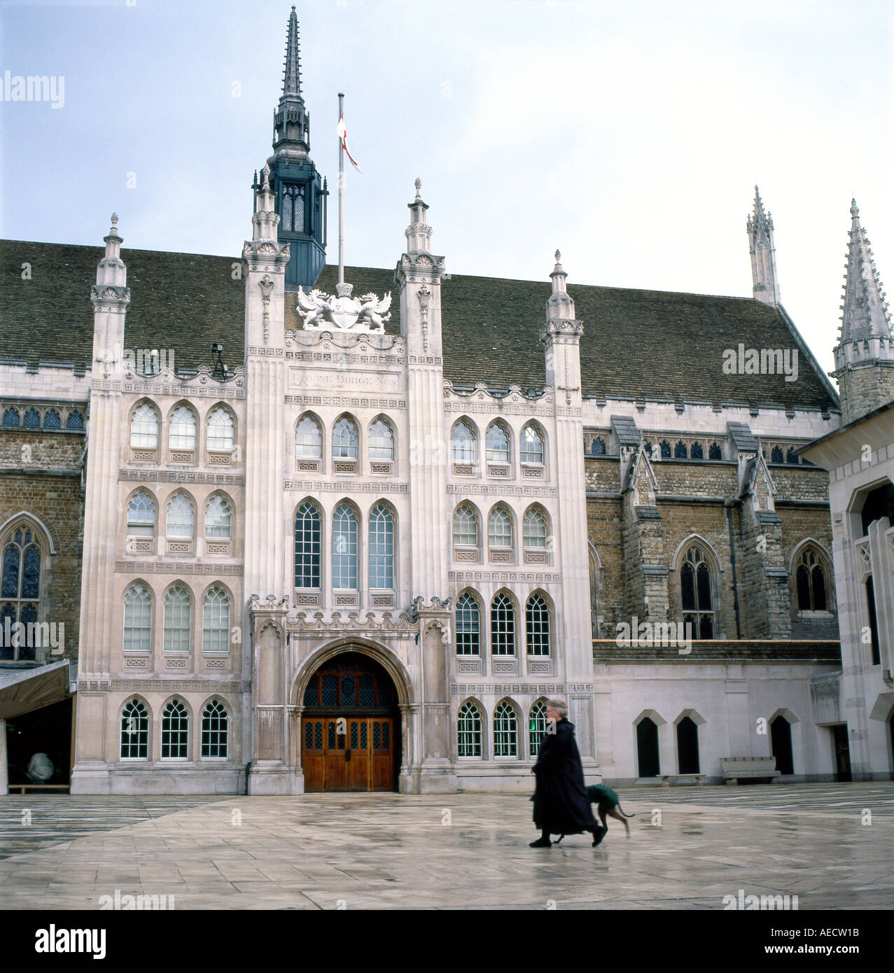 Ältere Frau trägt einen schwarzen Mantel wandern ein Hund im Hof vor dem Eingang zum Rathaus Großer Saal in der Stadt London UK KATHY DEWITT Stockfoto