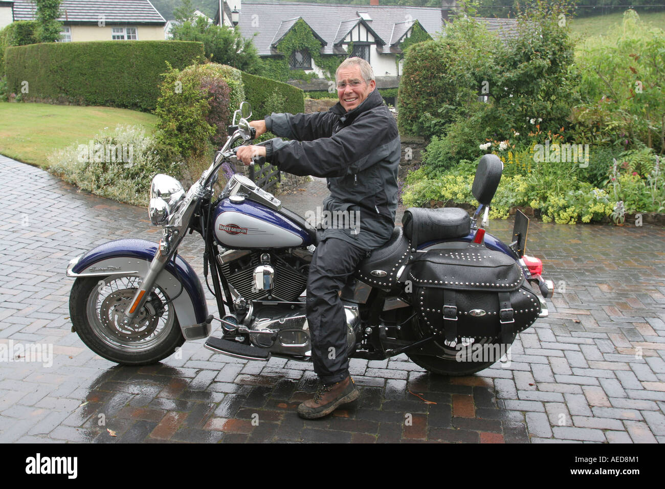 60 Jahre alten Mann mit Harley-Davidson Motorrad außerhalb seines Hauses Leute Lifestyle Wales Stockfoto