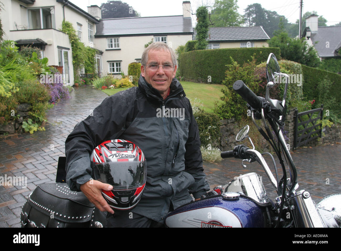 65 Jahre alter Mann mit Harley Davidson Motorrad außerhalb seines Hauses Leute Lifestyle Wales Stockfoto