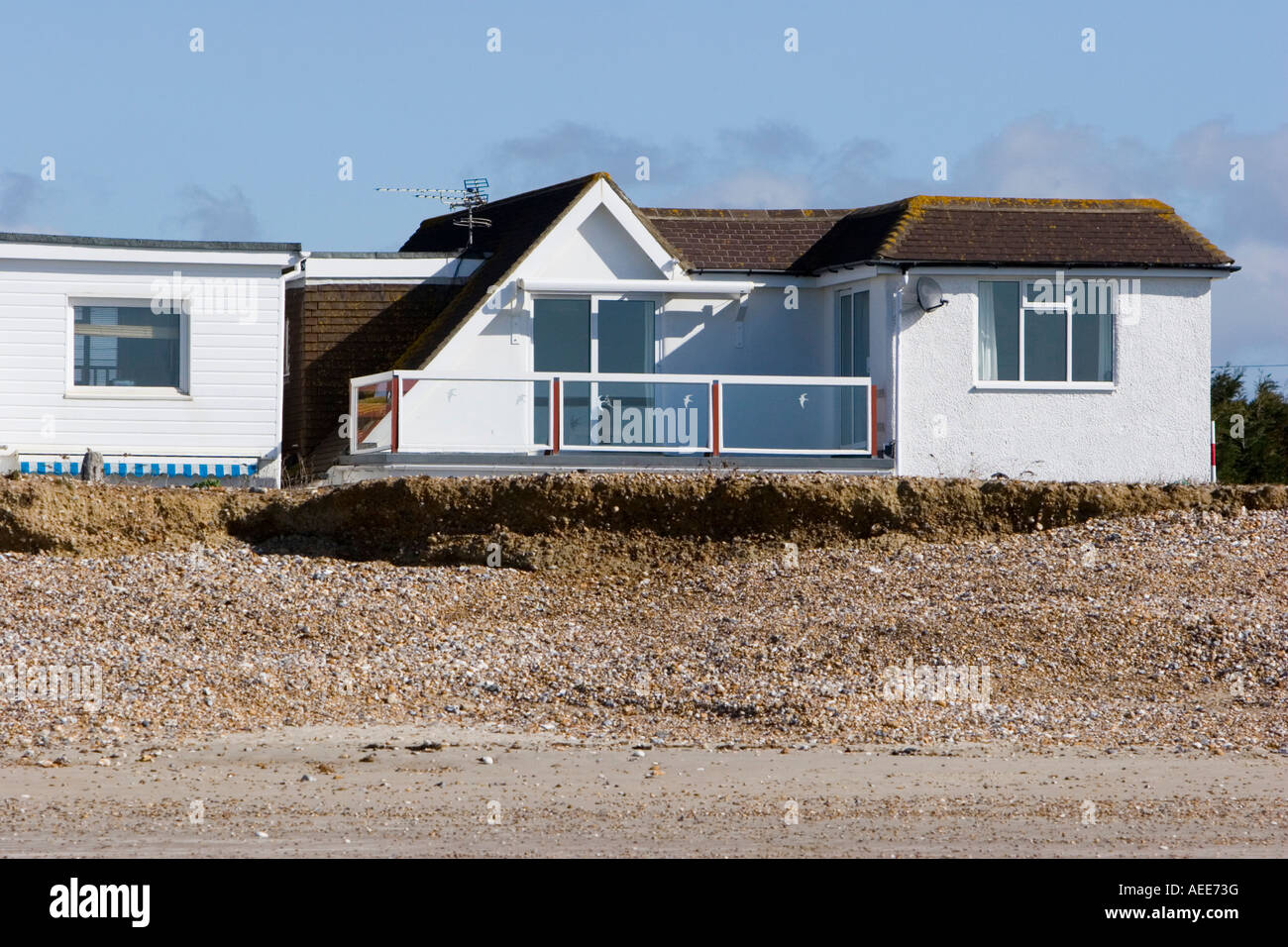 Häuser sehr nah an der Spitze der Erosion an einem Strand in Sussex Stockfoto