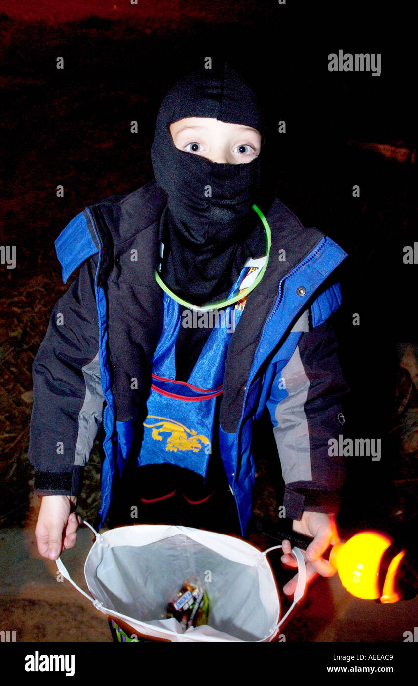 Kind im Ninja-Kostüm, die Öffnung der Tasche für Leckereien während Sie Süßes oder Saures zu Halloween Stockfoto