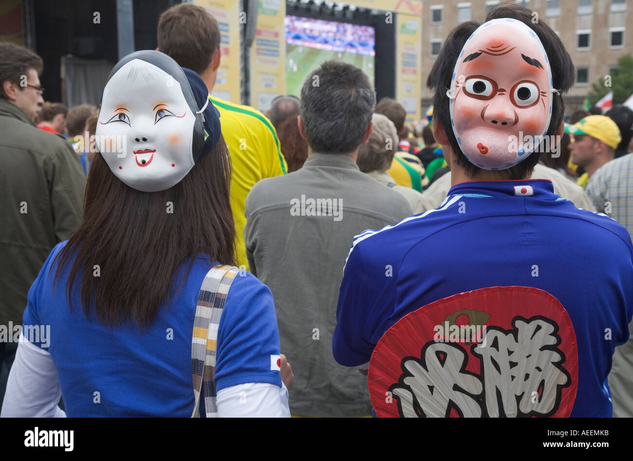 Zwei japanische Fußball-Fans mit lustigen Masken auf der Rückseite des Kopfes bei einer Fußball World Cup public-Viewing-Veranstaltung in Dortmund Stockfoto