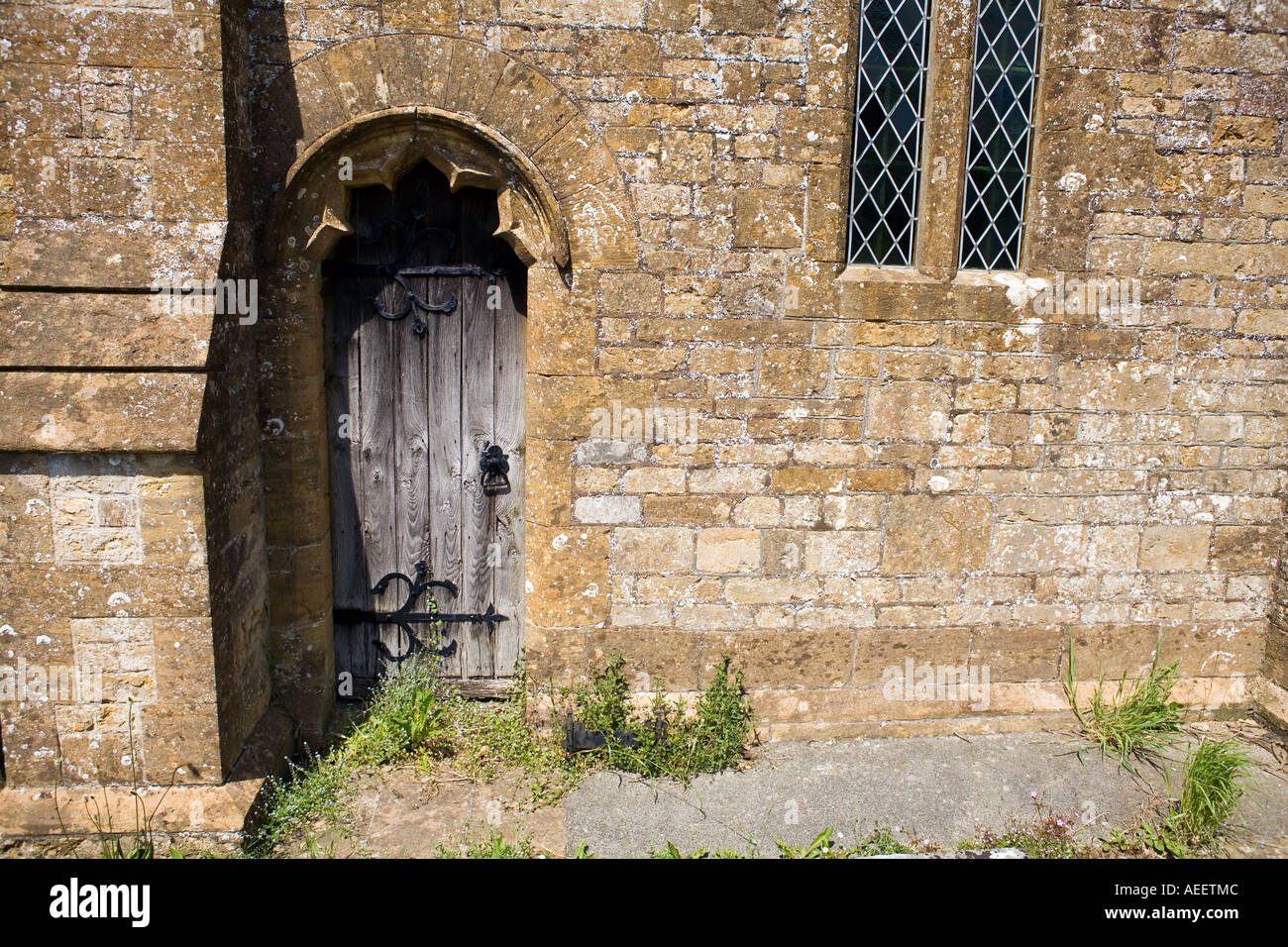 Alte hölzerne Seitentür in St. Johannes der Täufer Kirche Broadwindsor Dorset alte hölzerne Tür verknoteten Holz Stein Seitenwand Stockfoto