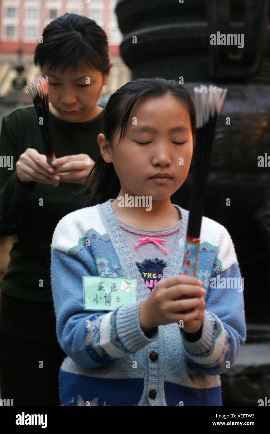 Shanghai, China. Mutter und Tochter brennende Räucherstäbchen an der Jade-Buddha-Tempel. Stockfoto