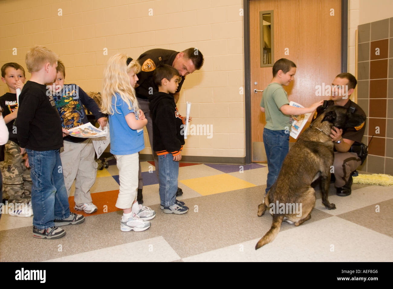 Kinder vom Kindergarten Klasse anstellen an Pet und Petting Polizeihund Fonz Stockfoto