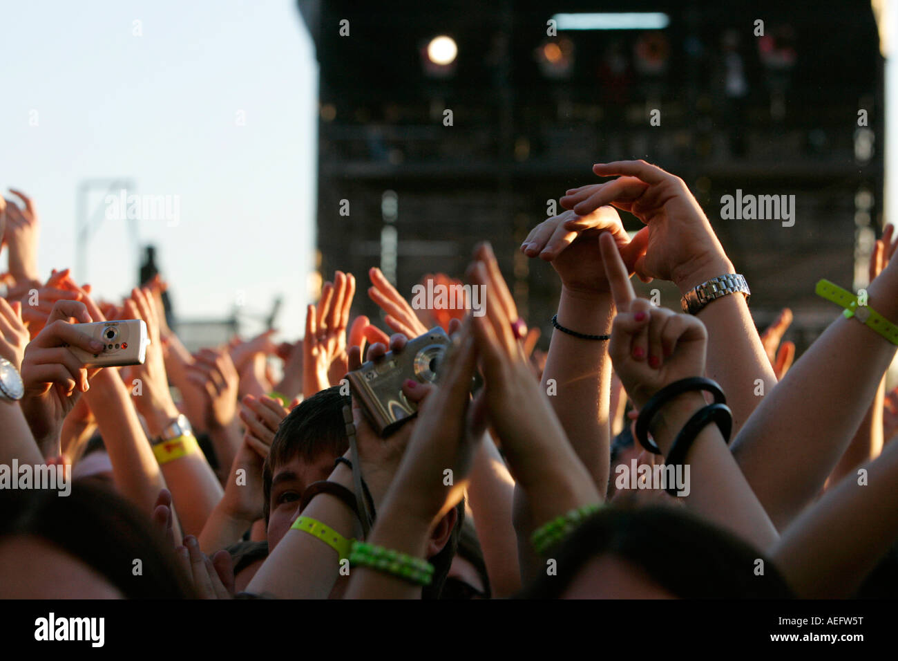 Fans bei einem open Air Konzert winken ihre Arme in die Luft und Fotografieren mit Kameras und Kameras Belfast Telefon Stockfoto