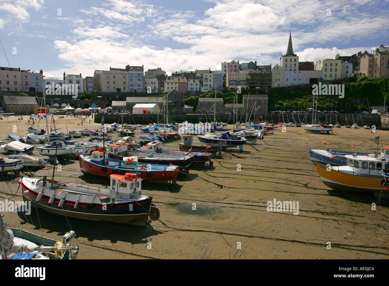 Boote liegen am Strand bei Ebbe in Tenby Hafen mit typischen bunten Hotels über Pembrokeshire Wales Großbritannien GB UK Stockfoto