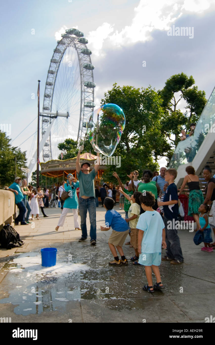 Vertikale Ansicht der Straßenkünstler riesige Luftblasen unterhaltsam eine Schar von Kindern auf der Southbank in London zu schaffen. Stockfoto