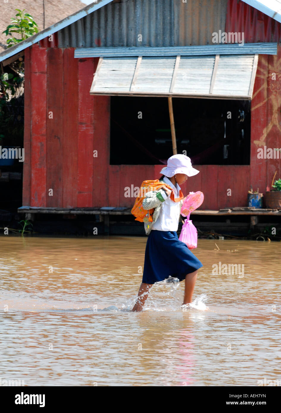 Kambodscha, Siem Reap, Tonle Sap See, Phnom Krom, süßen jungen Dorfmädchen in Uniform watet nach Hause von der Schule auf überfluteten Weg Stockfoto